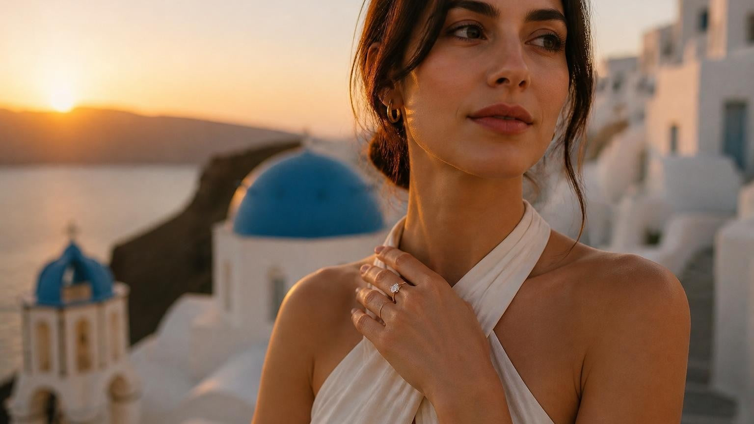 Best engagement rings in Santorini — elegant Greek woman with Satéur Destinée Ring, Oia blue domes at sunset