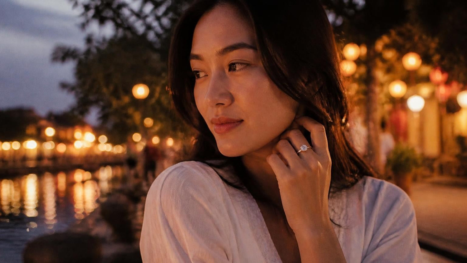 Best engagement rings in Vietnam — elegant woman with solitaire ring, Hội An lanterns at dusk