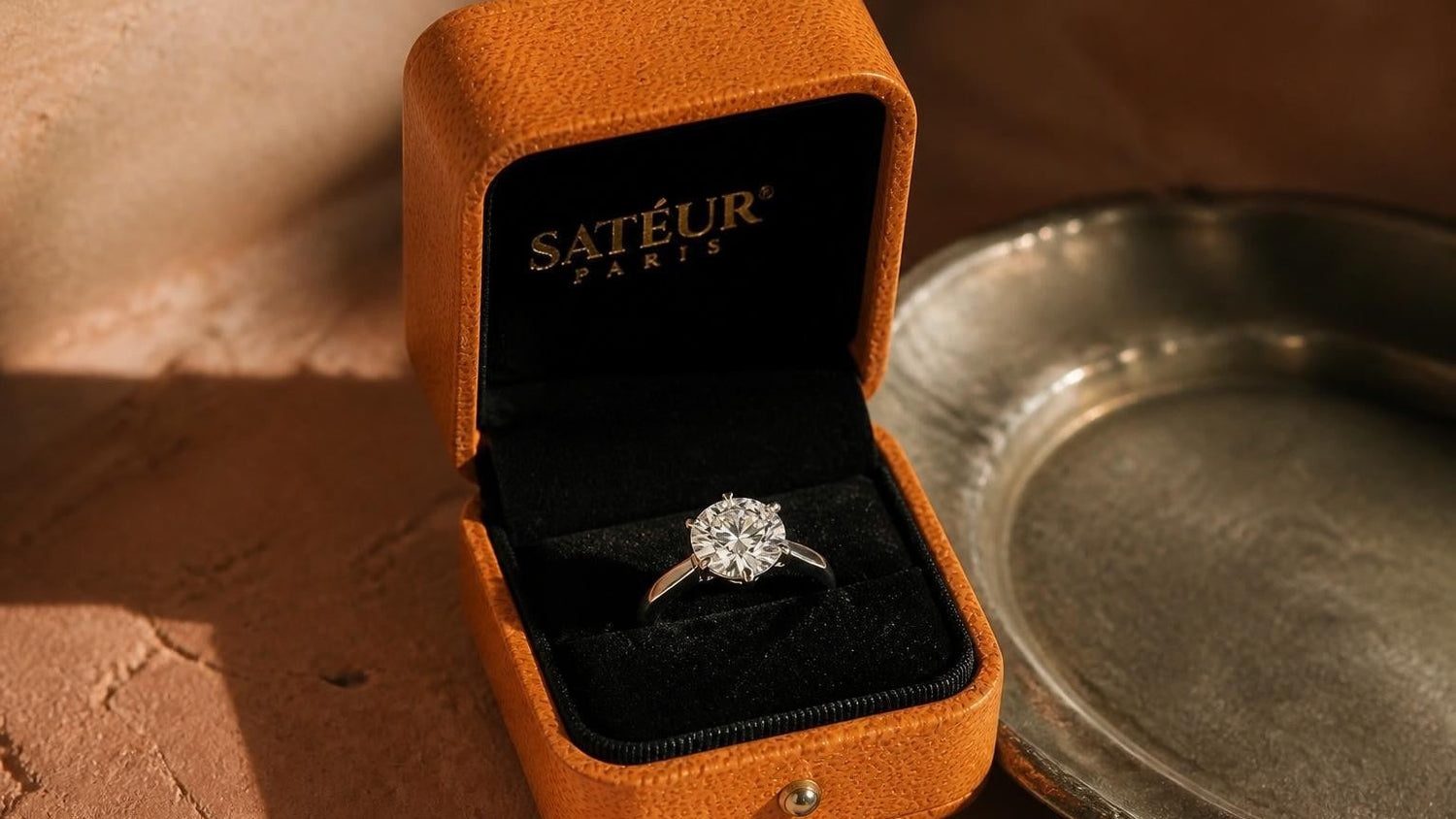 Open Satéur ring box with moissanite engagement ring — warm terracotta editorial