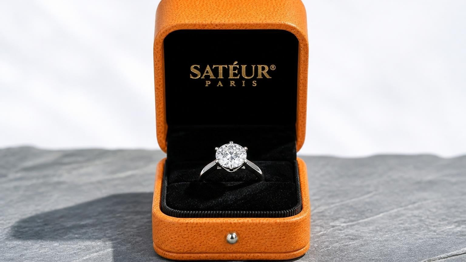 Real diamonds vs synthetic diamonds — open Satéur box with lab diamond ring on silver-grey slate