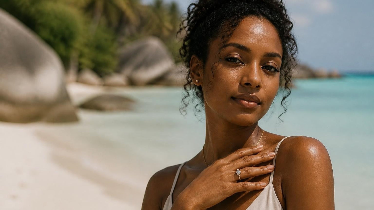 Best engagement rings in Seychelles — elegant Creole woman with solitaire ring, Anse Source d'Argent granite boulders and turquoise water behind
