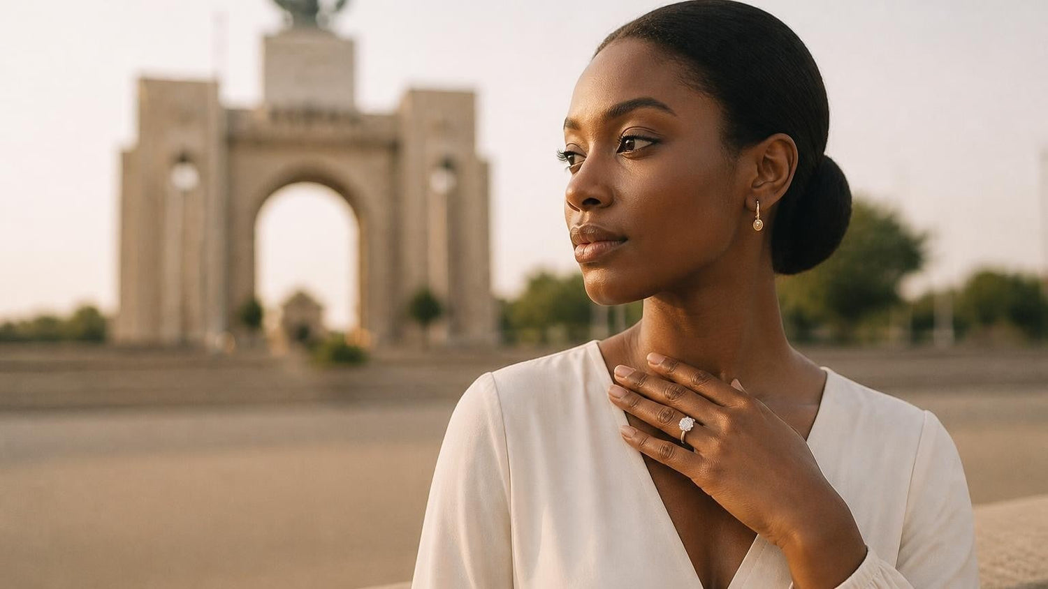 Best engagement rings in Togo — elegant Togolese woman wearing a Satéur Destinée solitaire ring, Monument de l Indépendance softly blurred behind her