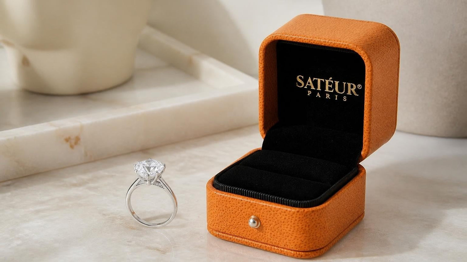 hidden halo engagement ring beside open orange Satéur ring box