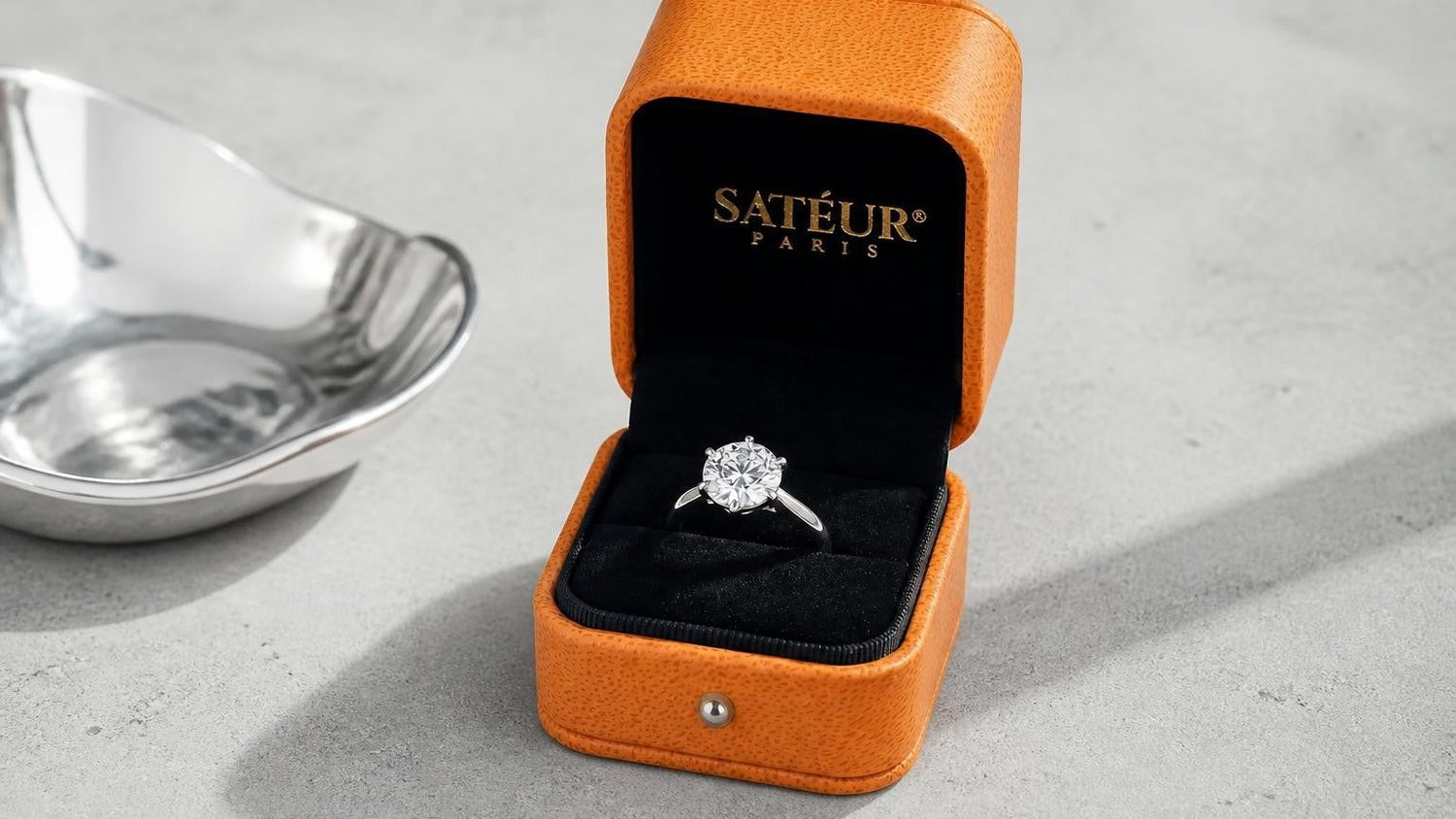 Popular engagement ring styles — open Satéur box solitaire ring on stone surface