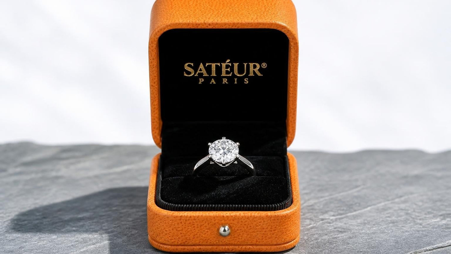 Real diamonds vs synthetic diamonds — open Satéur box with lab diamond ring on silver-grey slate